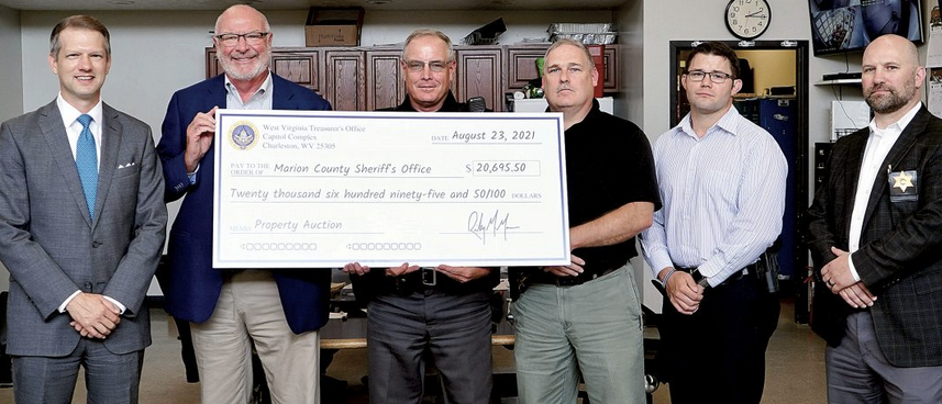 Moore presents $20K firearms auction check to police